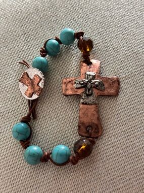bracelet with turquoise-colored beads and a hammered copper cross charm